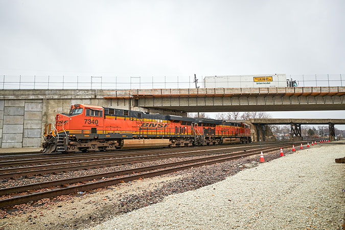 Construction underway at the Cicero Intermodal Facility, with BNSF locomotives on the track below a bridge as a J.B. Hunt truck drives by. 