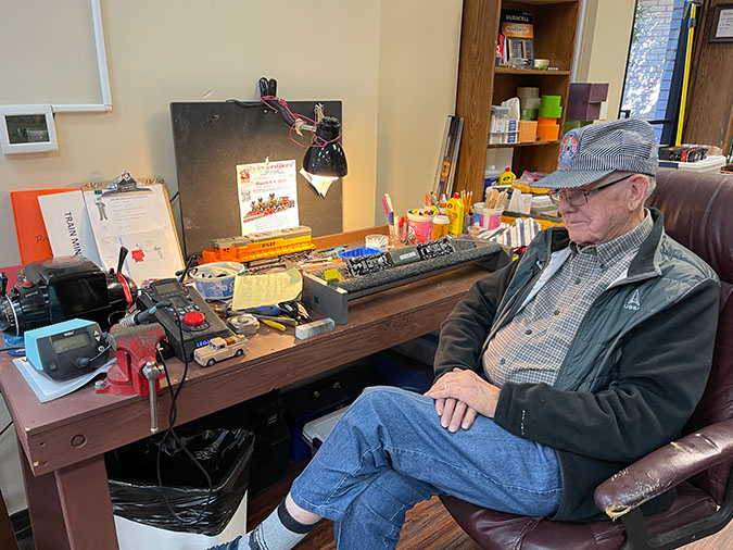 Harold Bryan sitting next to a desk inside White’s Chapel Methodist Church, with supplies to fix and maintain the trains